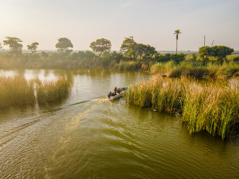 Aerial view of a boat with people navigating through tall reeds at Haleji Lake Thatta, Sindh, Pakistan.