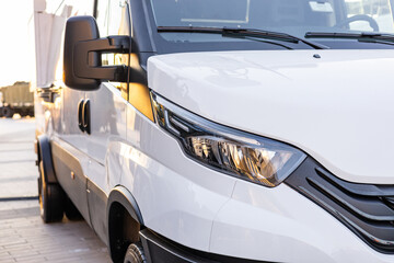Military equipment and army equipment.. Efficient commercial delivery vehicle illuminated by sunset sunlight. Cargo van in urban environment shown during sunset with highlighted headlights © NastyaPhoto