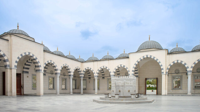 Symmetrical view of a mosque courtyard with a marble fountain and Arabic-style arcades during daytime