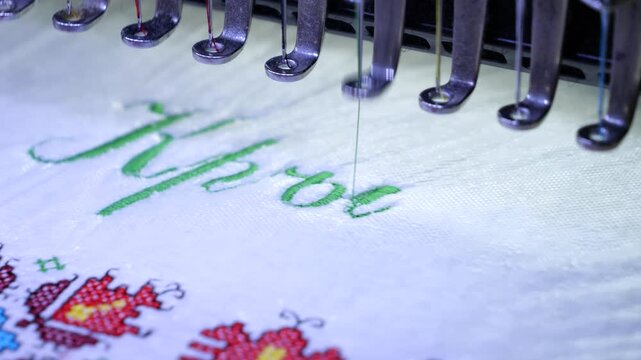 Machine embroidery of the inscription Holy Baptism with colored threads on a white terry cloth. Baptism cloth with cross stitch. Slow Motion 4k video.