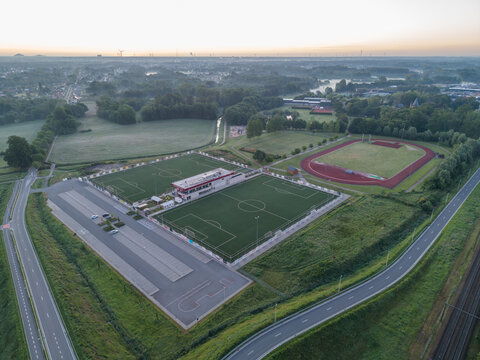 Diepenbeek, Belgium. Aerial drone view of sports complex with football fields and athletics track in green suburban landscape at sunrise