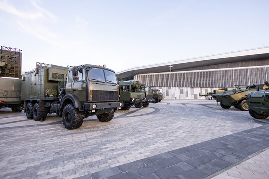 Military equipment and army equipment.. Support cars arranged precisely around production site during sunrise. Vehicles providing logistical support form precise lineup outside manufacturing