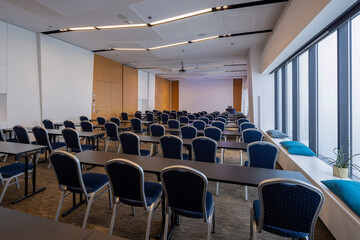 Fototapeta premium Empty modern conference room with rows of blue chairs tables and large panoramic windows