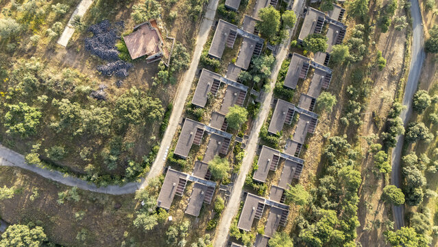 Aerial view of modern residential buildings arranged in rows on a green hillside with lush trees and winding roads in Andalusia, Spain.