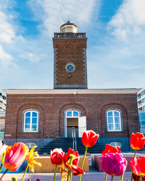The historic lighthouse at Lichttorenplein, a popular tourist attraction and information center, framed by colorful spring tulips in the heart of the coastal resort city, Knokke Heist, Belgium