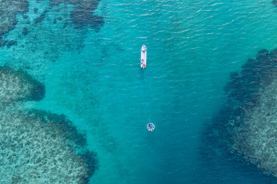Aerial view of a small boat and a circular floating platform on the turquoise waters of a coral reef near Naviti Island, Naviti, Western Division, Fiji.