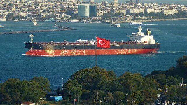 A large industrial oil tanker entering the Bosporus Strait from the Sea of Marmara past a waving Turkish flag towards Kadikoy in Istanbul, Turkey. Telephoto lens shot from Topkapi Palace