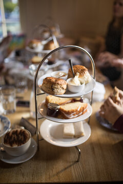 Traditional British afternoon tea stand with scones cream and sandwiches indoors