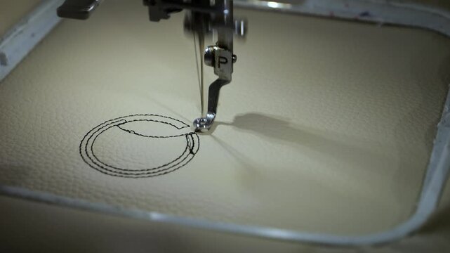Machine embroidery of circles with black thread on light brown leather fabric.