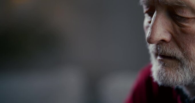 Close-up profile of elderly bearded man with serious thoughtful expression