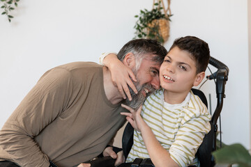 Obraz premium Father and son embracing in wheelchair with cerebral palsy