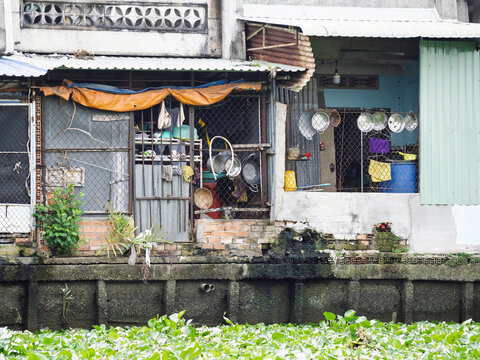 Canal-side informal housing with kitchen utensils and water hyacinth in Ho Chi Minh City, Vietnam
