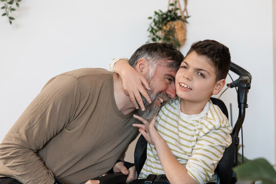 Father and son embracing in wheelchair with cerebral palsy
