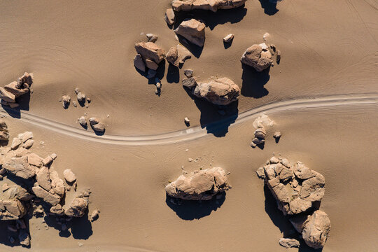 Aerial view of the Rock Tree formation and volcanic boulders scattered across the desert sand with vehicle tracks in Juntacha, Departamento de Potosi, Bolivia.