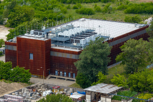 Aerial view of the Centrum Technologii ICM UW building with its rust-colored facade and rooftop cooling units surrounded by trees in Warszawa, Wojewodztwo mazowieckie, Poland.