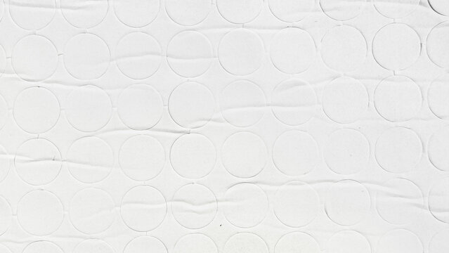 textured white paper background showcasing a geometric pattern of embossed circles on creased matte cardboard