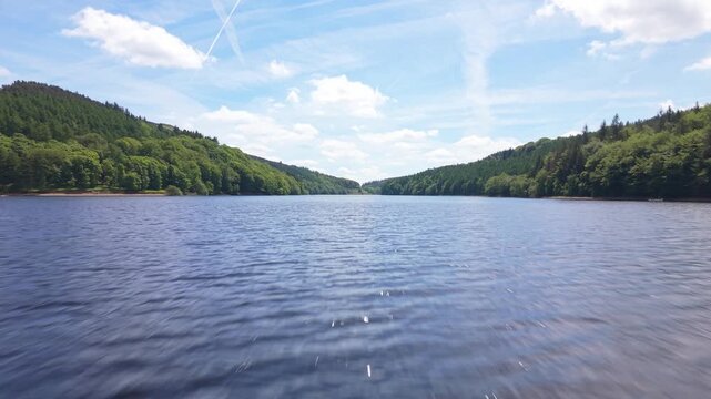 Aerial FPV Drone Footage Skimming Over Calm Water of Derwent Reservoir Surrounded by Forest in Peak District, England