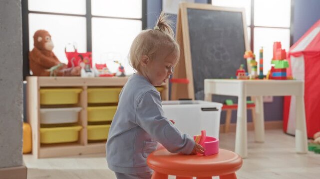 Girl holds colorful stacking cups and reaches out with hand in a building playroom; gentle curiosity.