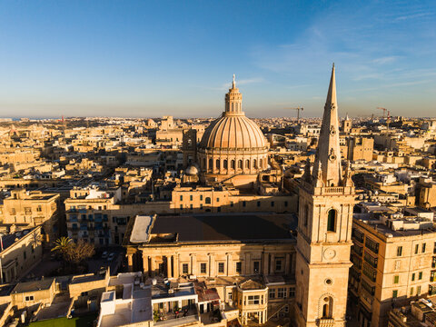 Aerial view of the iconic dome of the Basilica of Our Lady of Mount Carmel and the spire of St Paul's Pro-Cathedral over the historic rooftops of Valletta, Port Region, Malta.