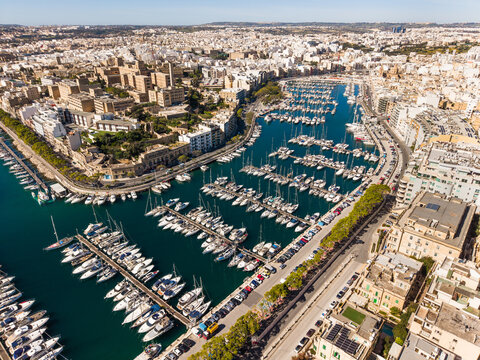 Aerial view of the Msida Marina filled with luxury yachts and boats surrounded by urban architecture and rooftops in Ta' Xbiex, Eastern Region, Malta.
