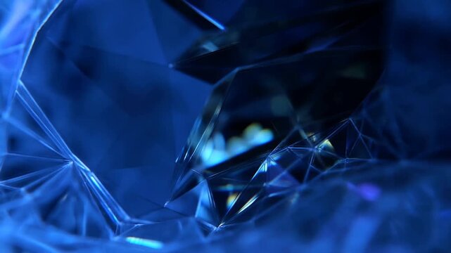 Dolly tracking slow motion of faceted crystal gem rotating and refracting light on blue studio background close up macro abstract geometry