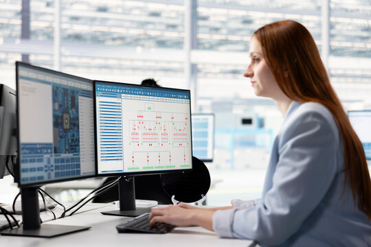 Woman evaluating microchip system architecture blueprints on office desk computer, Female engineer looking at EDA software interface on PC, doing electronic parts design automation.