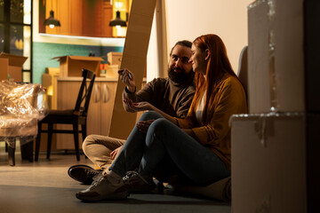 Obraz premium Holding keys, happy couple, home ownership, buying new house, celebrating life event together, Partners taking a break from moving and sitting on the floor, admiring their achievement.