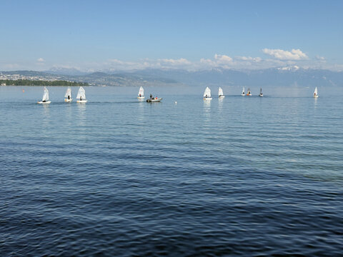 Several Sailing Boats Moored on the Calm Turquoise Waters of a Scenic Swiss Lake With Alpine Mountains Beyond