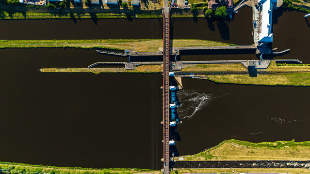 Aerial view of the Vltava river dam and locks with a bridge crossing the water and green banks in Veltrusy, Central Bohemian Region, Czechia.