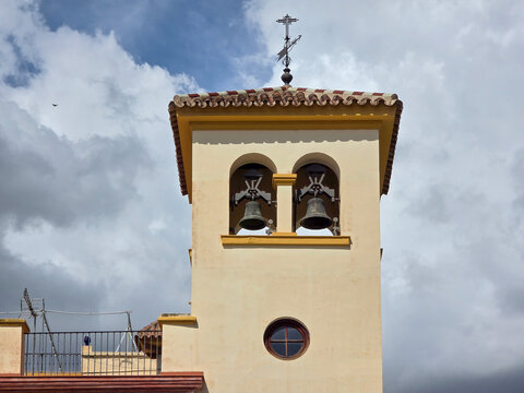 Historic Parroquia de San Pedro Church Bell Tower with Weather Vane and Arched Belfry against Cloudy Sky in Malaga Spain