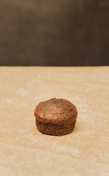 A chocolate muffin on a gold metal and black background