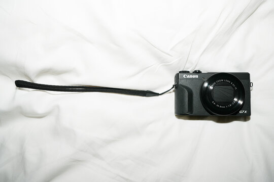 Canon PowerShot G7 X compact digital camera placed on white fabric background, showcasing portable photography equipment and consumer electronics