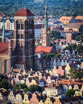 Aerial view of St. Mary's Church and the Main Town Hall rising above the historic red rooftops and colorful facades of the old town Gdansk, Pomeranian Voivodeship, Poland.