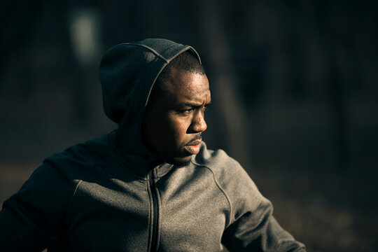 Focused runner in gray hoodie training outdoors at dusk