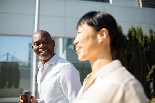 Two coworkers talking while walking outside office building
