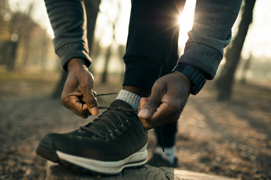 Runner tying shoelaces on park trail at sunrise