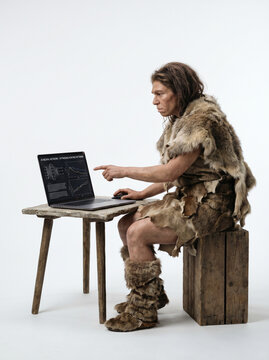 Caveman Analyzing Data On Laptop