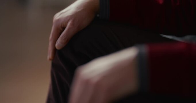 Close-up of a hand resting on a bent knee in soft indoor light