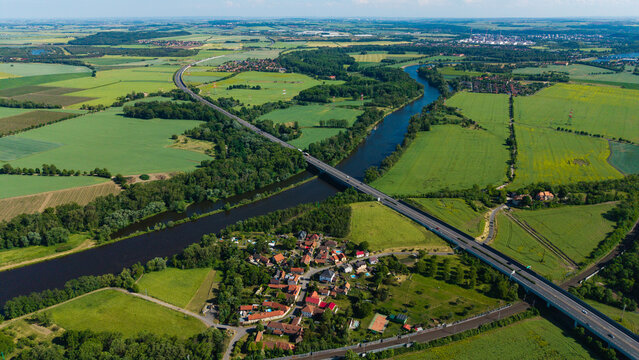 Aerial view of the Vltava river and the D8 motorway bridge crossing through lush green fields and the village of Mlcechvosty in Vranany, Stredocesky kraj, Czechia.