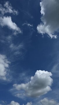 Vertical time lapse of white summer clouds drifting through a clear blue sky
