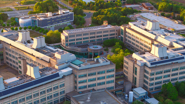 Aerial view of the GSK Stevenage research campus featuring modern laboratory buildings with rooftop ventilation systems and green trees in Stevenage, England, United Kingdom.