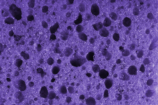 Macro, closeup of purple foam sponge texture with porous, spongy and bubbly surface pattern suitable for abstract background design. Foamed polyurethane material surface