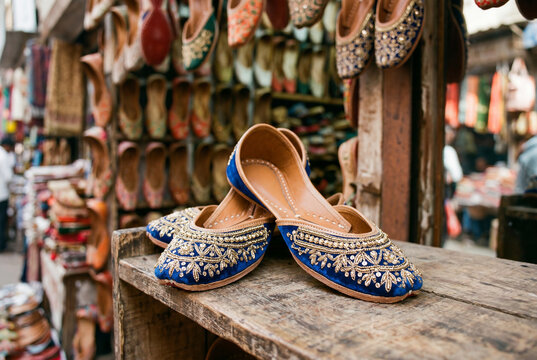 Traditional indian blue jutti shoes displayed on wooden stand in market