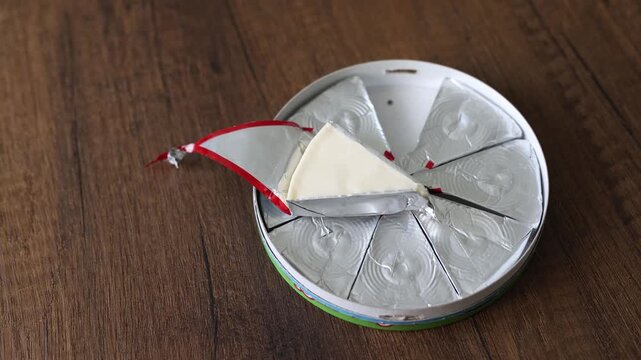Close-up of triangle processed cream cheese portion in open foil wrapper