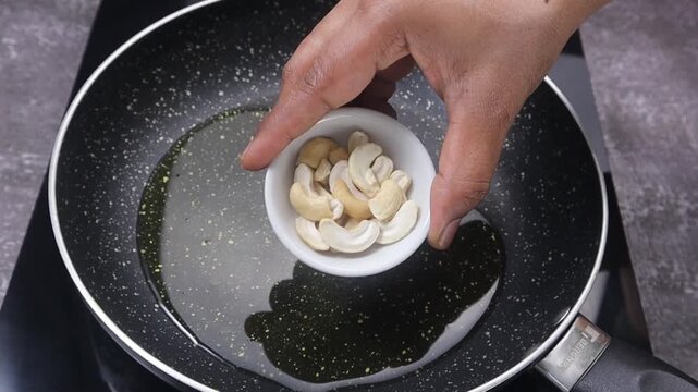 Roasting cashews and raisins in ghee in a pan until golden brown and plump