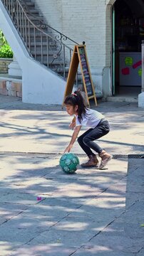Latina girl trying to kick a soccer ball in the park