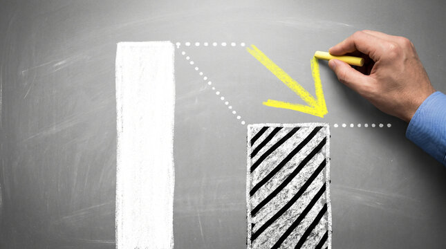 Hand drawing a declining bar chart on a chalkboard