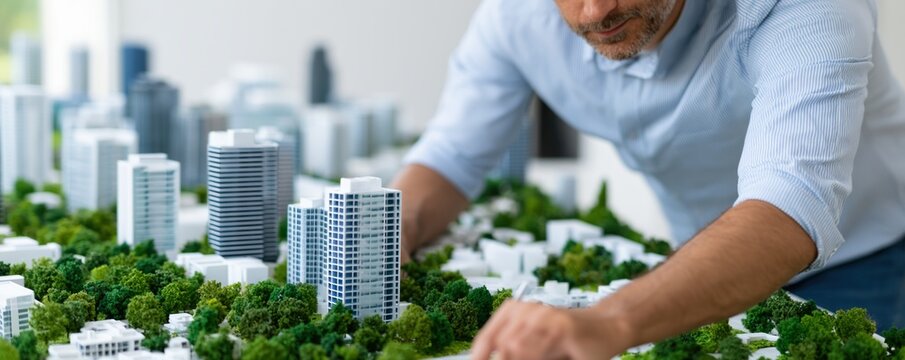 Urban planner analyzing a scale model of a future smart city with green spaces and infrastructure for planning presentation and sustainable development banner background