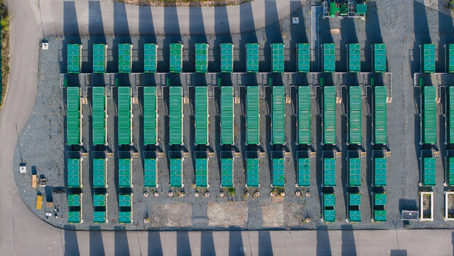 Aerial view of the Thurrock Battery Energy Storage BESS and Flexible Generation Plant with rows of green containers casting long shadows on gravel Thurrock, England, United Kingdom.