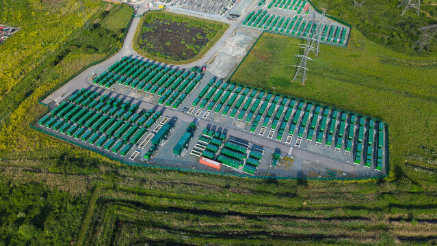 Aerial view of the Thurrock Battery Energy Storage BESS and Flexible Generation Plant with rows of green battery containers and power pylons in Thurrock, England, United Kingdom.